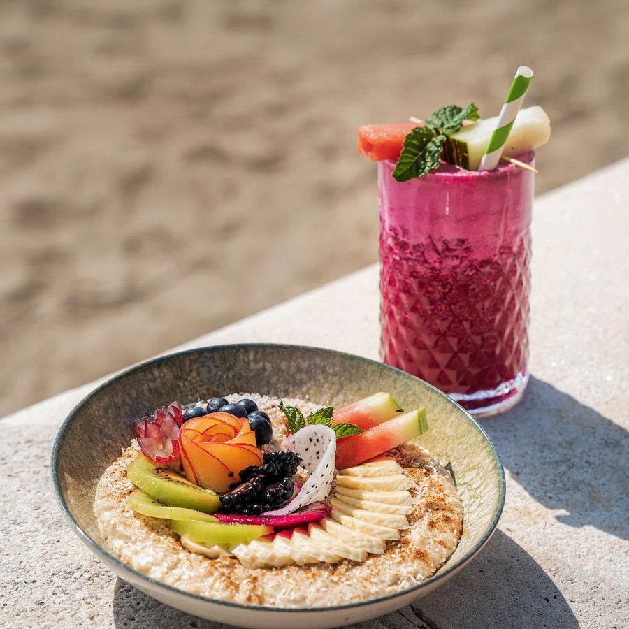 A smoothie bowl and a juice on the beach wall.
