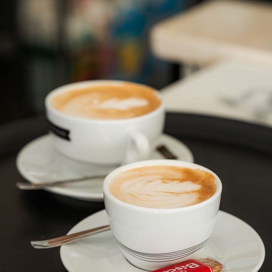Two cappuccinos on a marble table.