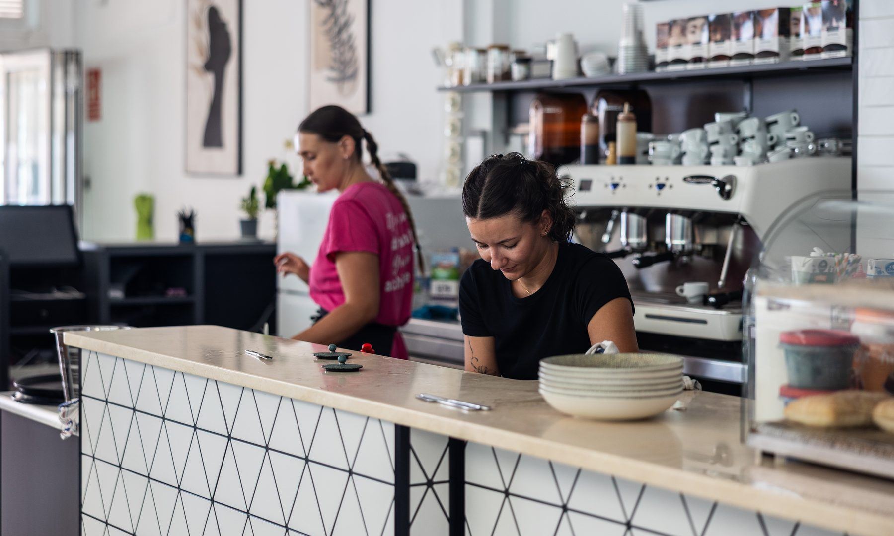 Two of the Café Nomad team behind the counter, in front of the espresso machine.